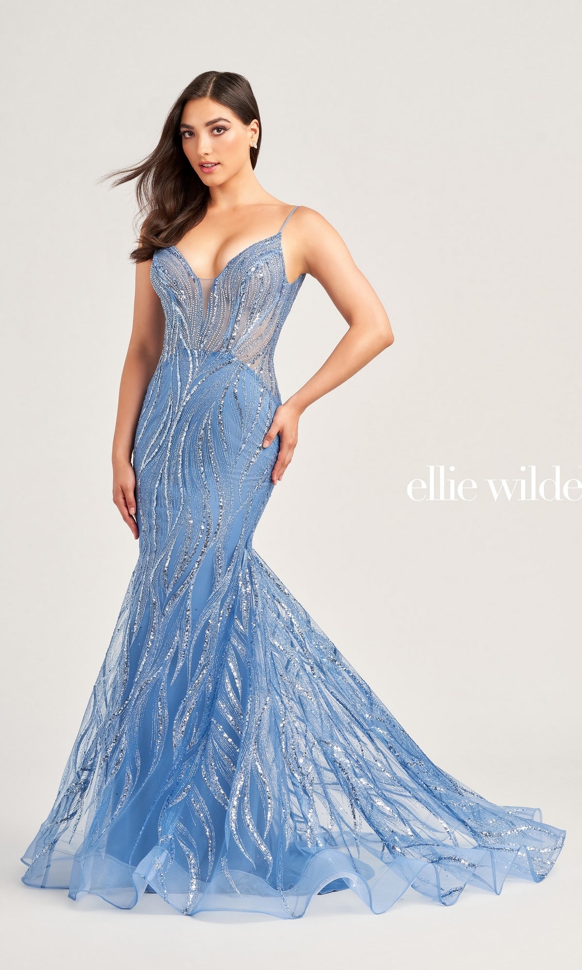 A woman poses in the Sheer-Bodice Long Ellie Wilde Prom Dress EW35098, a fitted floor-length light blue gown with silver sequin accents, a sheer bodice, and an elegant mermaid skirt.